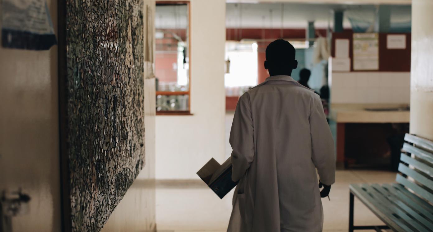 African doctor in white medical gown walking through the hospital lobby in village in Africa.