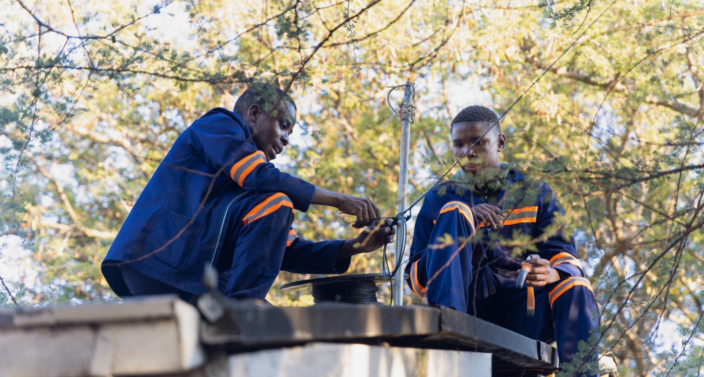 fiber optic cable install, african workers on the roof, roll of cable to install residential internet