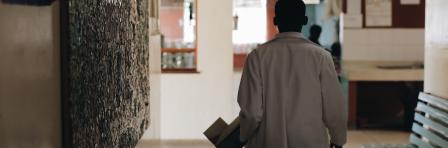 African doctor in white medical gown walking through the hospital lobby in village in Africa.